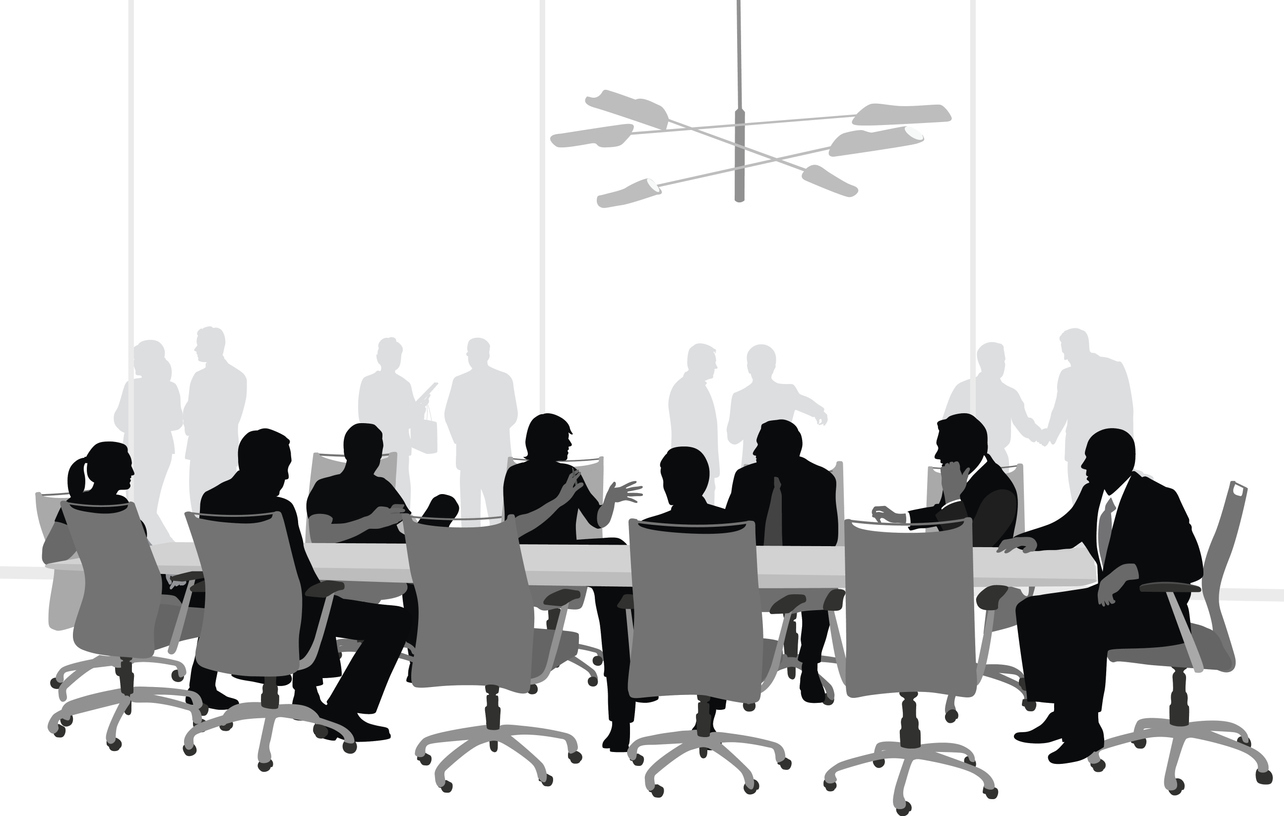 A black and white silhouette image of a group of business people seated at a boardroom table. 